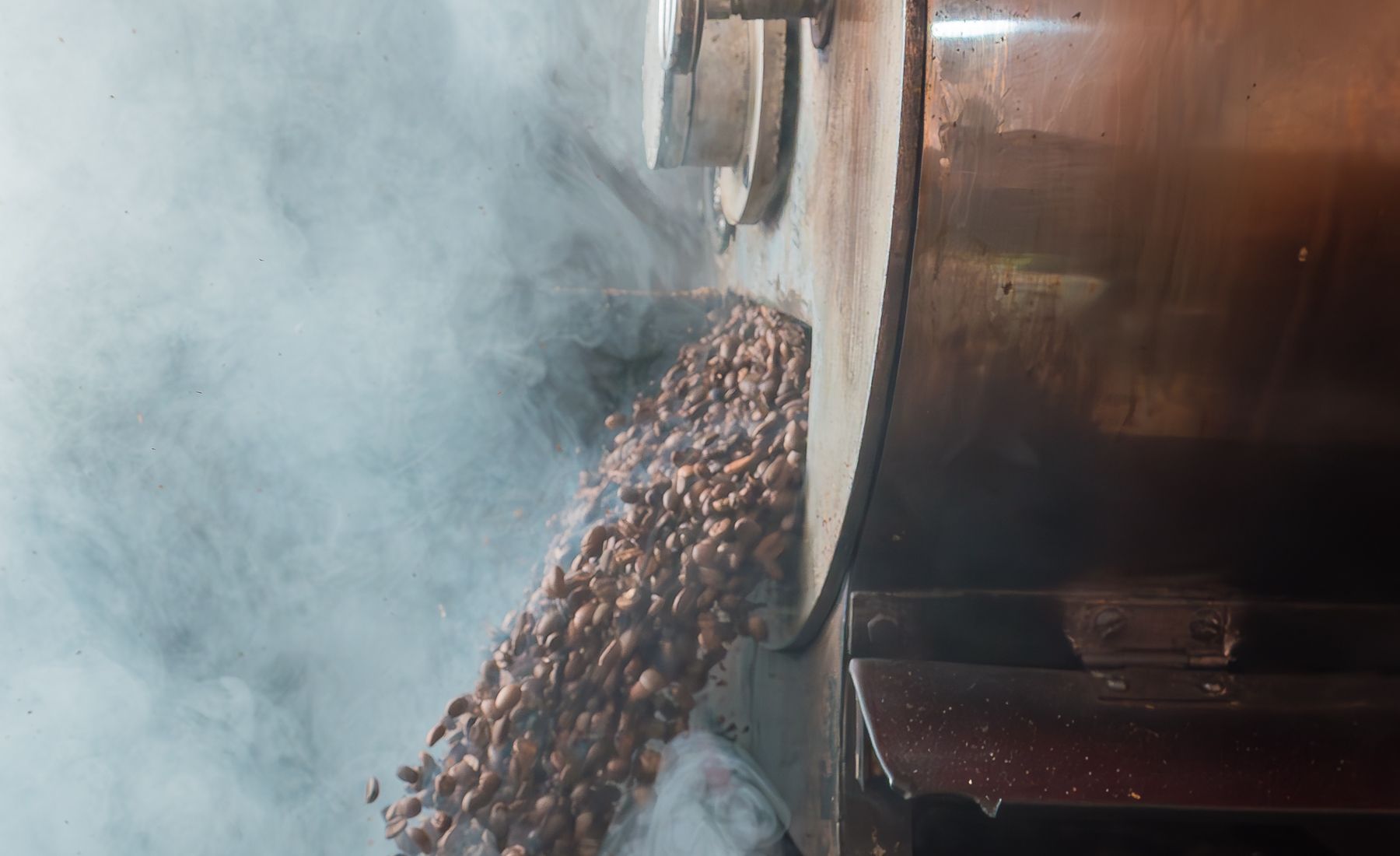 Steam rising off freshly roasted beans as they leave the drum